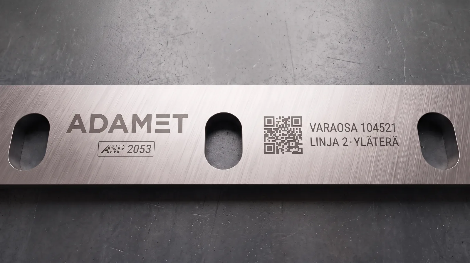 Terän kylkeen etsatut merkinnät: Adamet-logo, QR-koodi, varaosanumero, linjatunnus ja ASP 2053 -materiaalileima